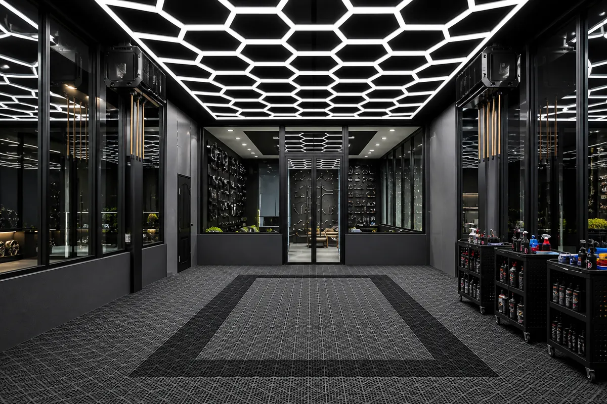 Showroom automóvel com piso modular cinzento e teto de luzes hexagonais